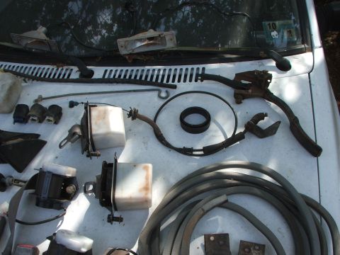 1991 Ford Festiva - Assorted car parts are displayed on the hood of a white vehicle.