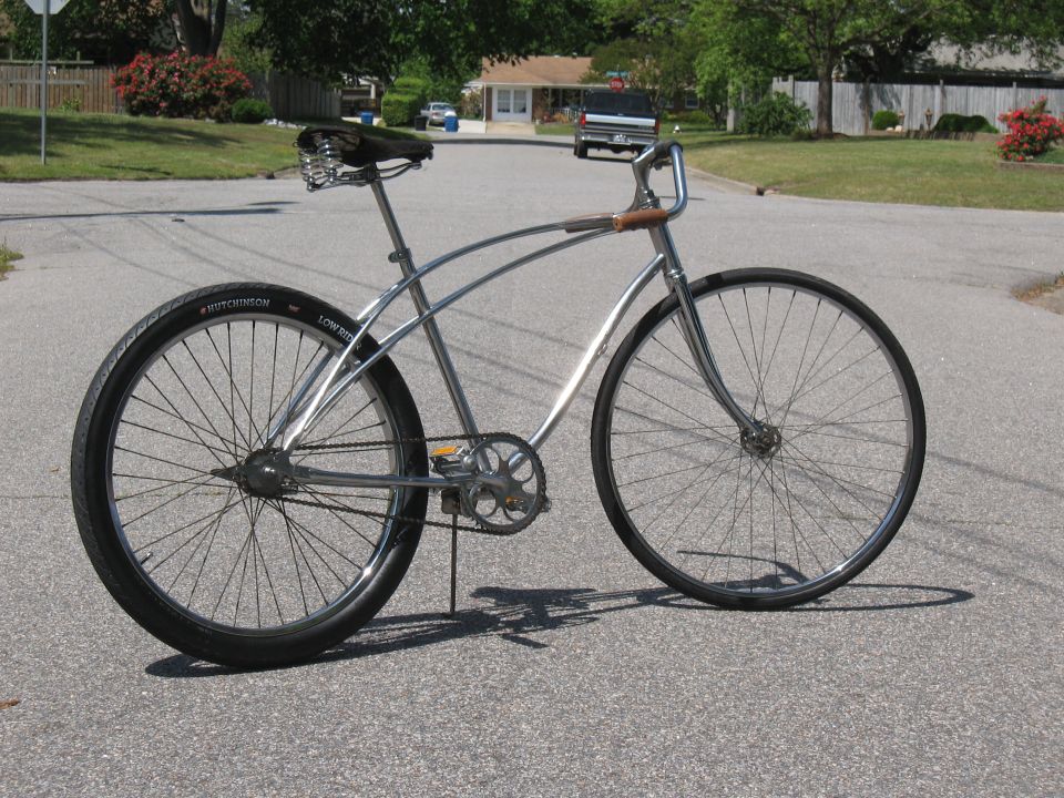 Chrome cruiser bicycle with black tires and a spring seat, parked on a suburban street