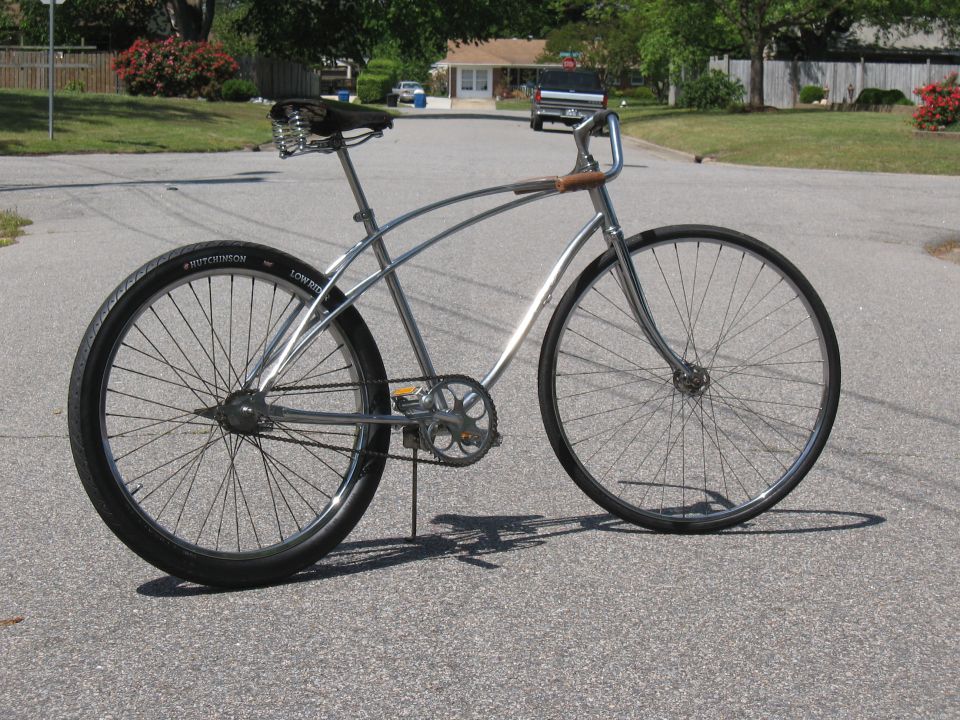 Chrome bicycle with black tires and a sprung seat, parked on asphalt