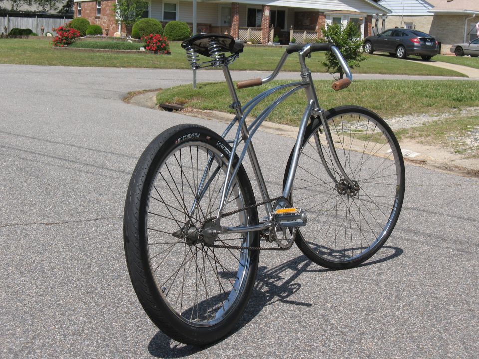 Chrome cruiser bicycle with wide tires and sprung seat, seen from rear