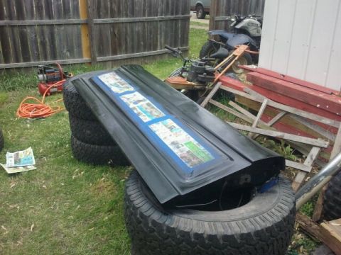1979 Ford Bronco - A car hood is propped up on tires, displaying a collage of taped-together images.