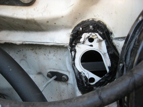 1994 Ford Bronco - Firewall grommet area with sealant, likely for wiring or hoses, in a vehicle's engine bay.