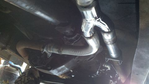 1978 Ford Bronco - The exhaust system of a vehicle is shown from underneath, new chrome piping and flexible sections.