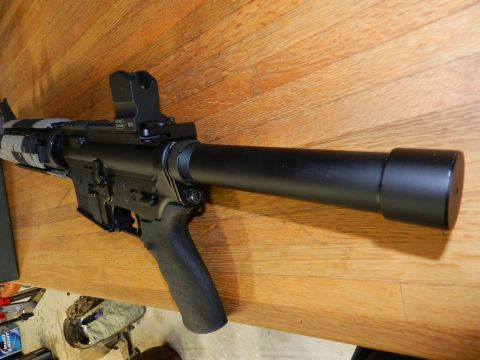 1996 Ford Bronco - Close-up of an assault rifle with a suppressor attached, resting on a wooden surface.