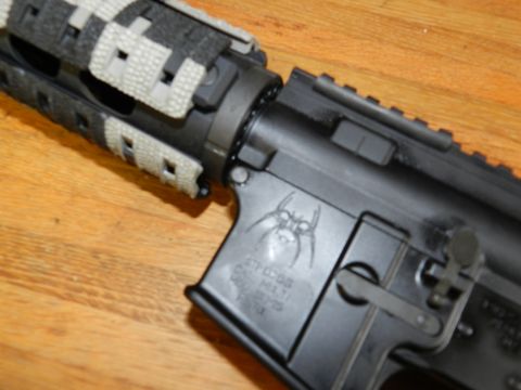 1996 Ford Bronco - Close-up of an AR-15 lower receiver showing a spider logo and caliber markings.