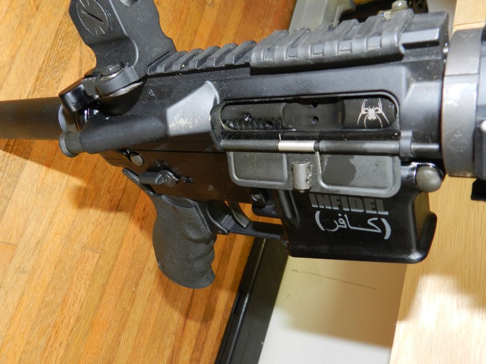Close-up of an AR-15 style rifle receiver with a spider logo and "INFIDEL" text