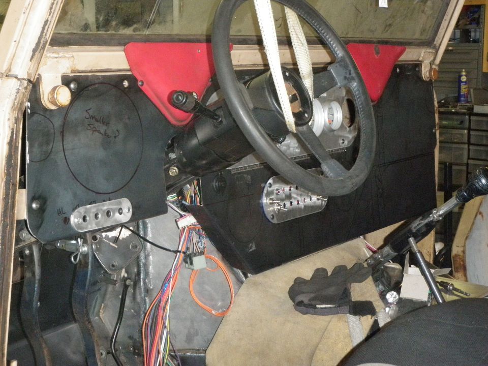 Dashboard and steering column of a vehicle being worked on, with exposed wiring and custom panels