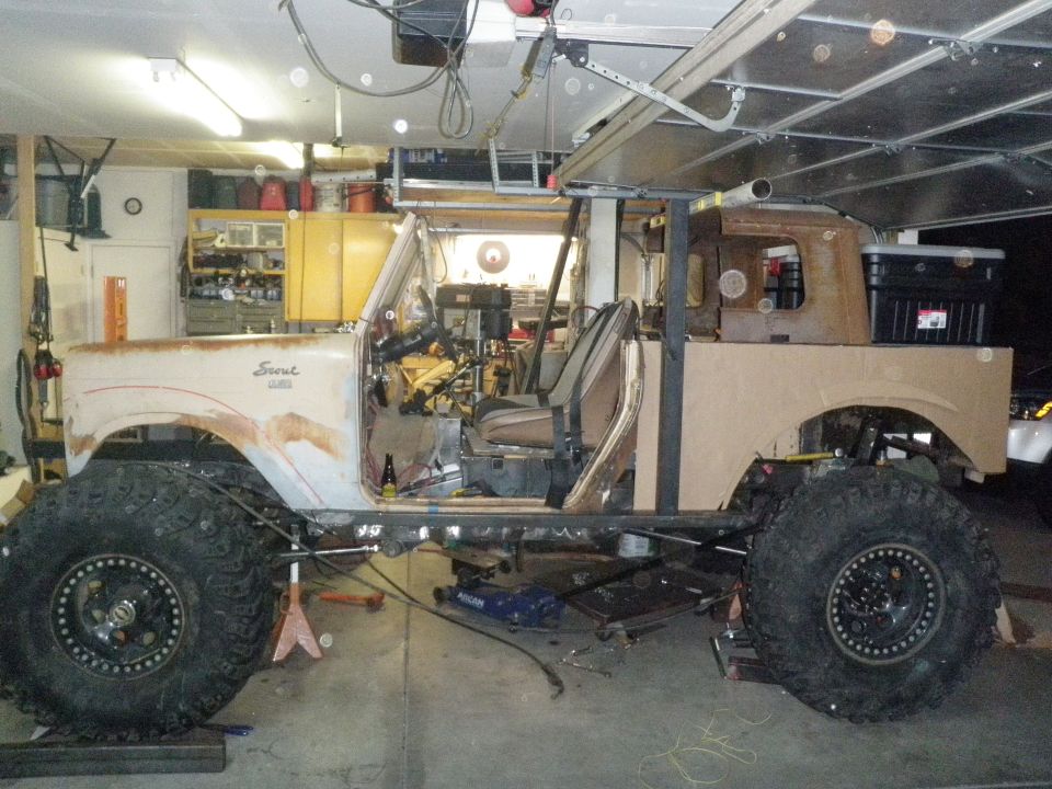 Customized International Scout with large tires, undergoing modifications in a garage