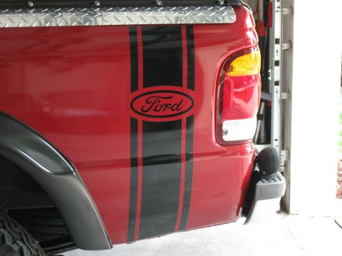 1999 Ford Ranger - This red Ford pickup truck features black racing stripes and a Ford emblem on its rear side panel.