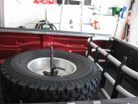 1999 Ford Ranger - Spare tire and jack secured in the bed of a red pickup truck.