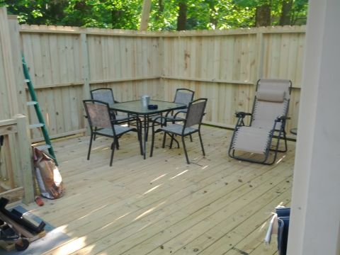 1979 Ford F-150 - A wooden deck area is furnished with a table, chairs, and a lounge chair, with a ladder nearby.