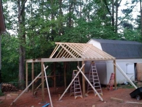 1979 Ford F-150 - A construction site shows framing for a new roof extension next to a white shed.