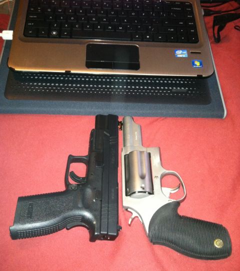 2006 Ford E350 - Two handguns are placed next to a laptop on a red surface.