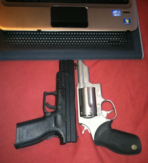 2006 Ford E350 - Two firearms, a pistol and a revolver, are displayed next to a laptop computer on a red fabric surface.
