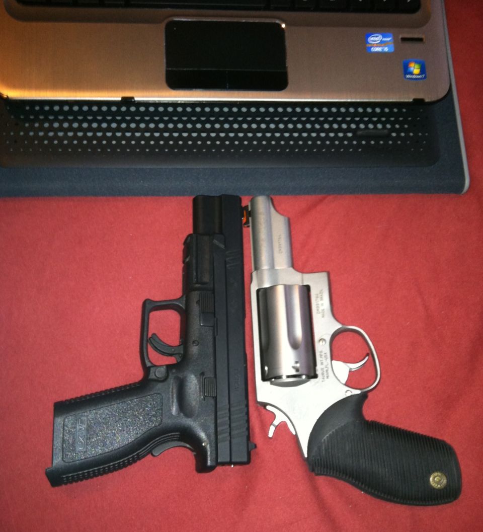 Black semi-automatic pistol and silver revolver next to a laptop on a red surface