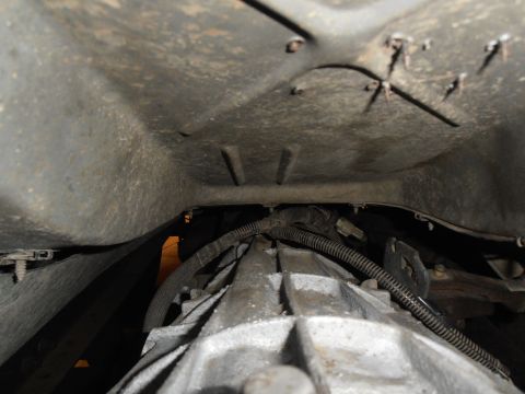 1990 Ford Bronco - Underside view of a vehicle's transmission and frame, showing wiring and metal components.