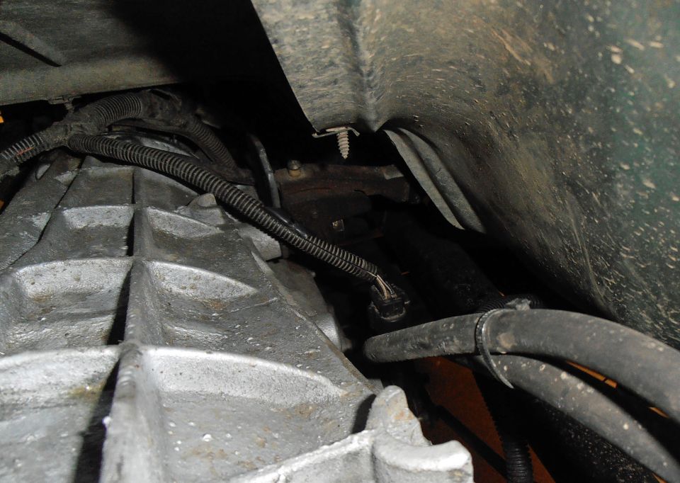 Close-up of a transmission housing with wiring and hoses attached