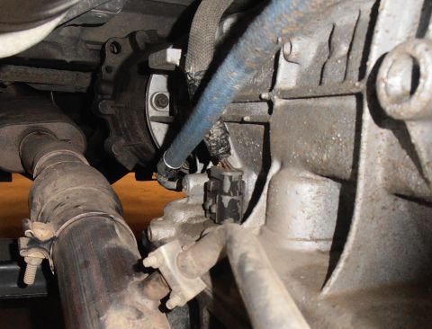 1990 Ford Bronco - Underside view of a vehicle's transmission housing and exhaust pipe.