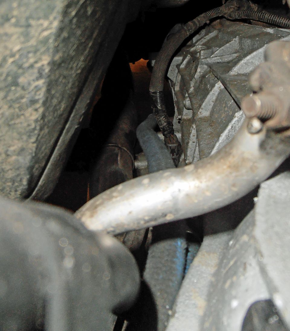 Close-up of vehicle transmission housing, exhaust pipe, and wiring harness