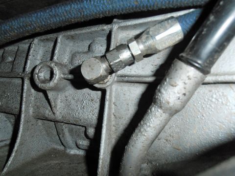 1990 Ford Bronco - Transmission fluid line fitting connected to a metal component.