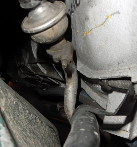 1990 Ford Bronco - Detail of an engine component, showing a vacuum line and metal tubing.