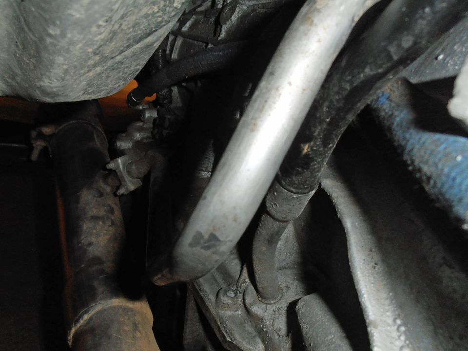 Aluminum tube routed past dirty engine parts and hoses underhood