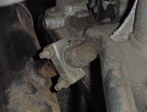 1990 Ford Bronco - Close-up view of an exhaust pipe bracket attached to a vehicle's engine block.