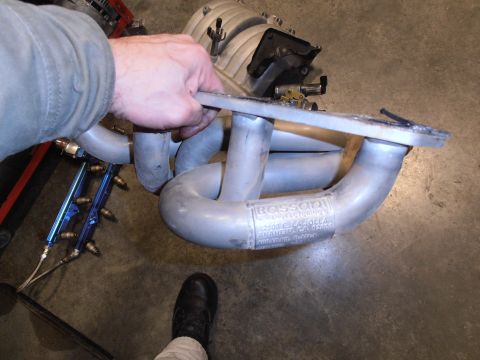 1990 Ford Bronco - A hand holds a Bassani exhaust manifold, showing the manufacturer's label and address.