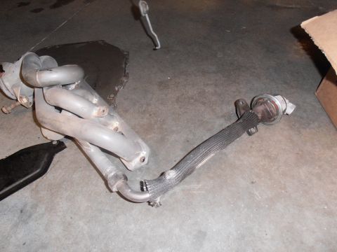 1990 Ford Bronco - Exhaust manifold and flexible pipe with actuator shown on a concrete surface.