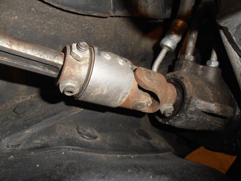 1990 Ford Bronco - A close-up view of a steering universal joint, showing its rusty metal components and attached tubing.