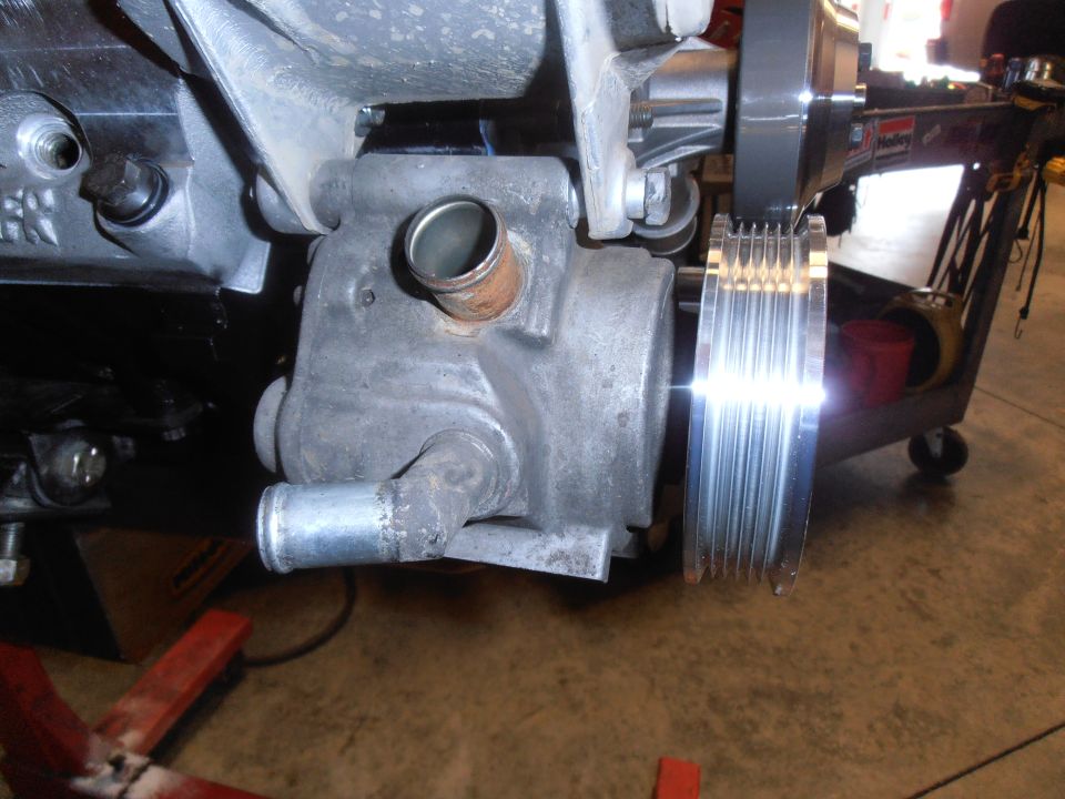 Aluminum engine-mounted pump with polished serpentine pulley on a red stand