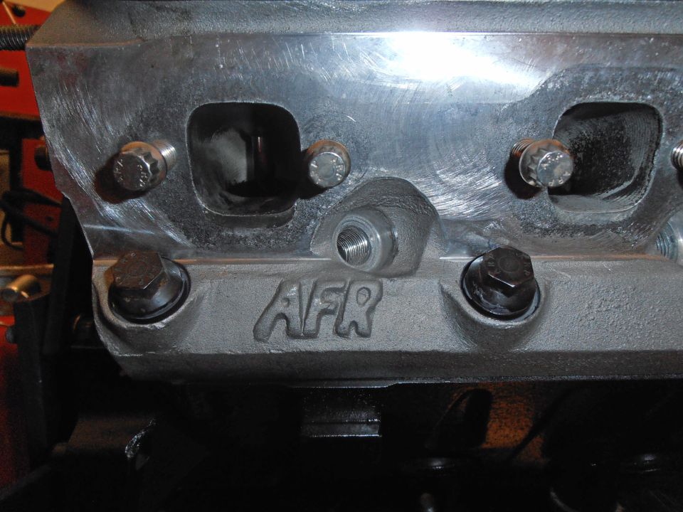 Aluminum engine cylinder head with AFR logo, showing bolt holes and intake ports