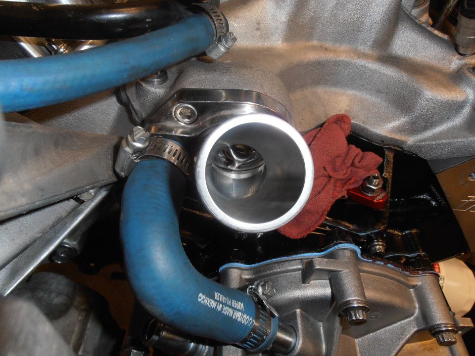 Polished stainless thermostat housing on intake manifold with thermostat visible and blue hoses