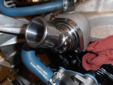 1990 Ford Bronco - A shiny thermostat housing is connected to blue hoses on an engine, with a red rag resting on the side.