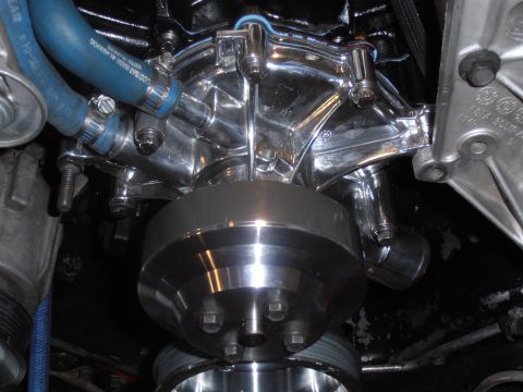 1990 Ford Bronco - Close-up of a polished chrome water pump and pulley system, connected by a blue hose.
