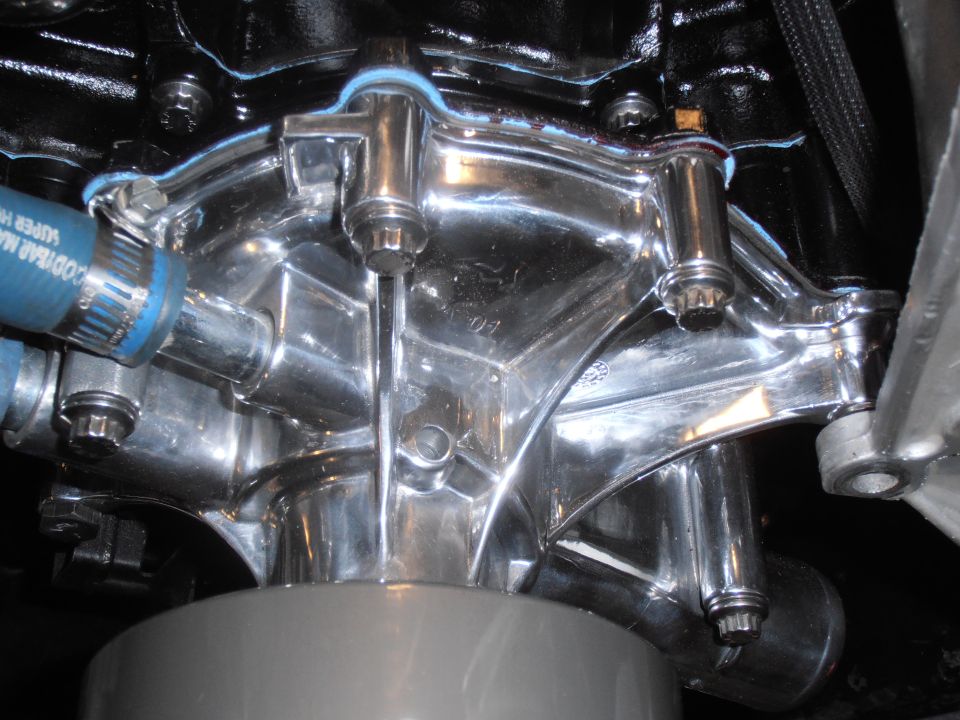 Chrome water pump assembly with blue hose attached to engine block