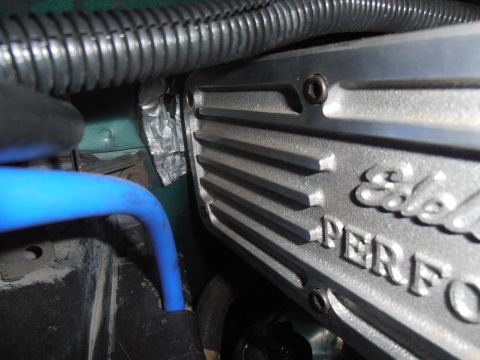 1990 Ford Bronco - Close-up view of an engine's Edelbrock Performance valve cover, partially obscured by a blue hose and wiring loom.