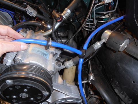1990 Ford Bronco - Close-up of a vehicle's air conditioning compressor with blue hoses attached.