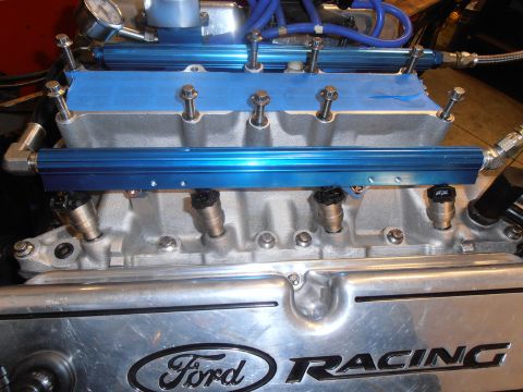 1990 Ford Bronco - Top-down view of a bare aluminum EFI intake manifold on a V8 with blue anodized billet fuel rails mounted on both banks, four visible fuel…