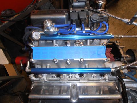 1990 Ford Bronco - Close-up of an engine's fuel rail system, showing blue hoses and a pressure gauge.