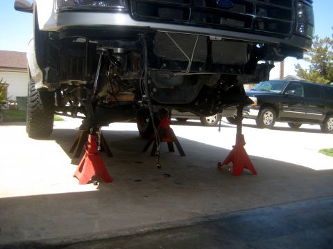1996 Ford Bronco - Undercarriage of a vehicle being worked on, supported by red jack stands.