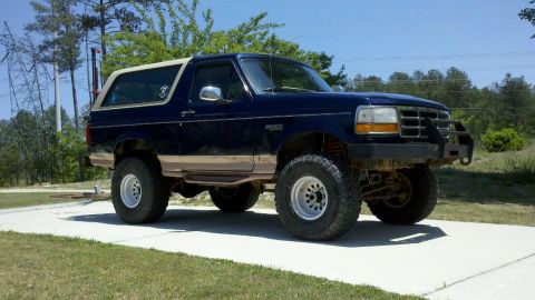 1995 Ford Bronco - This lifted 1995 Ford Bronco features a dark blue exterior with tan trim and a white removable roof.