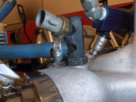 1990 Ford Bronco - Close-up view of engine components including fuel injectors and a blue hose attached to the intake manifold.