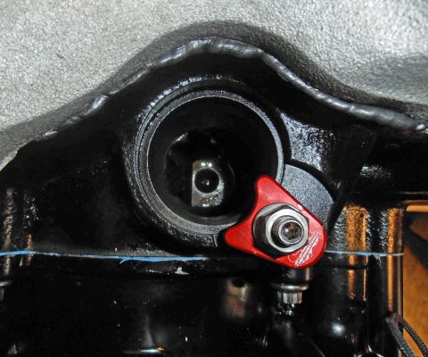1990 Ford Bronco - A red engine component is attached to a black metal part with a bolt.