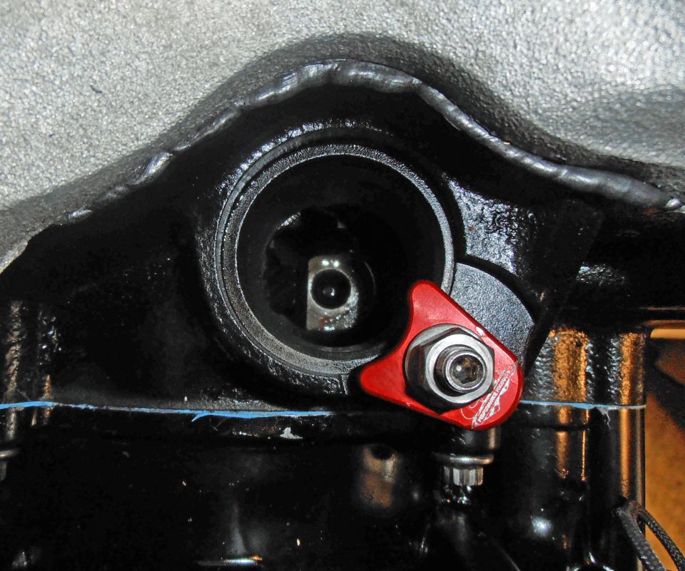 Close-up of a red engine component with a bolt and some text on it
