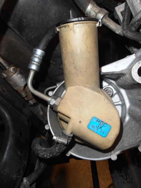 1990 Ford Bronco - Close-up of a power steering fluid reservoir with a blue sticker.