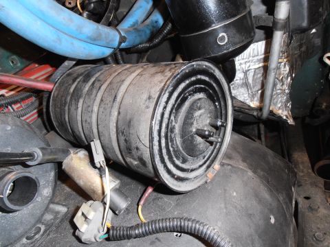 1990 Ford Bronco - Close-up view of an engine component, likely part of the emissions system, with visible hoses and electrical connectors.