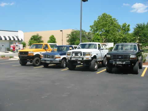 1992 Ford Bronco - Several Ford trucks are parked in a lot on a sunny day.