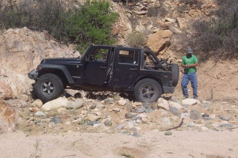 1981 Ford F-150 - A black Jeep Wrangler sits on a , rocky path with a person standing nearby.