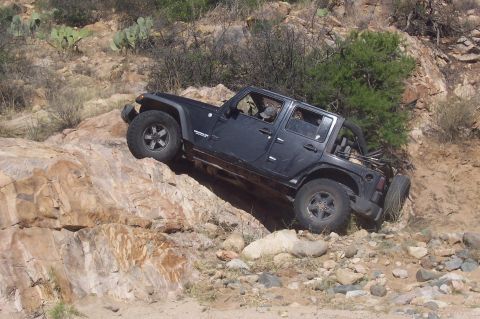 1981 Ford F-150 - A black Jeep Wrangler navigates a steep, rocky incline in a desert environment.